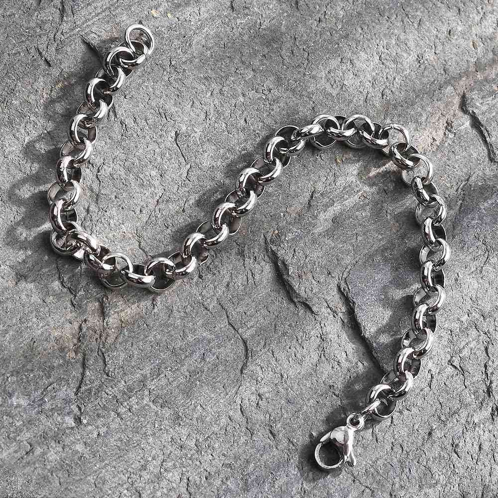 silver tone rolo chain bracelet over grey rock surface. 