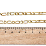 golden Figaro link bracelet with lobster claw clasp displayed above a wooden ruler on white background. 