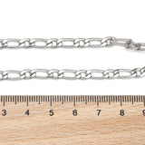 silver Figaro link bracelet with lobster claw clasp displayed above a wooden ruler on white background. 