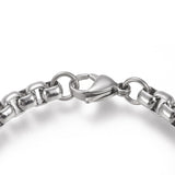 zoomed in section of silver tone large box chain bracelet with lobster claw clasp over white background. 