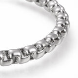 zoomed in section of silver tone large box chain bracelet over white background. 