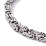 zoomed in section of silver Byzantine chain bracelet on white background. 