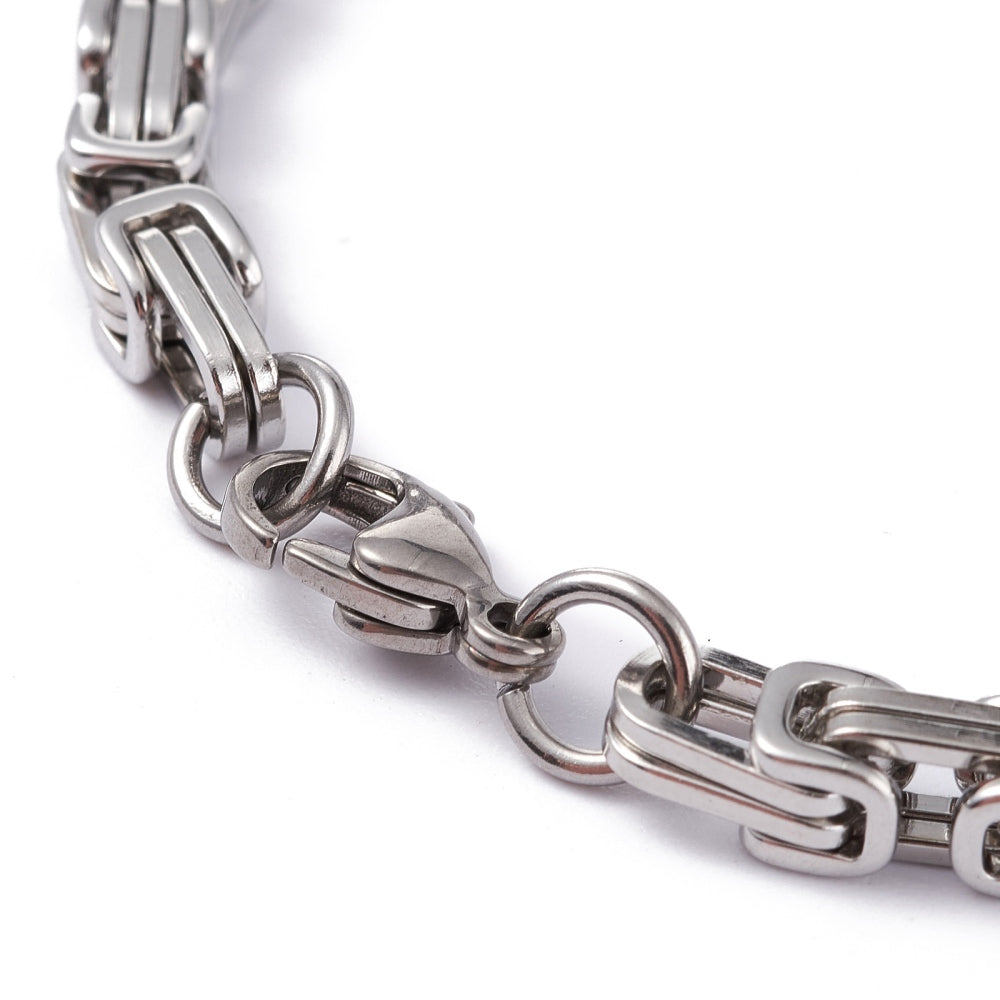 zoomed in section of silver Byzantine chain bracelet with lobster claw clasp on white background. 
