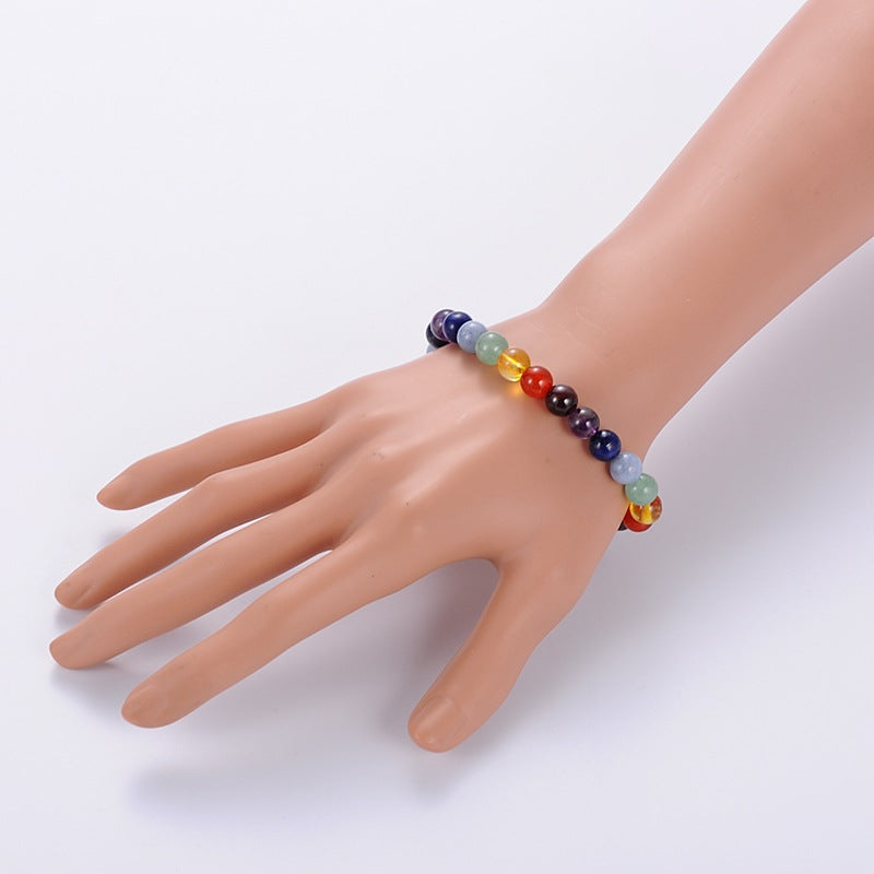 gemstone repeating round chakra stone bead bracelet displayed on mannequin hand over white background. 