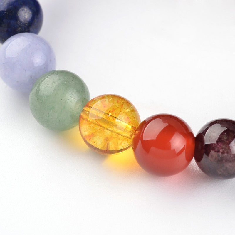 zoomed in section of round chakra stone bead stretch bracelet over a white background. 