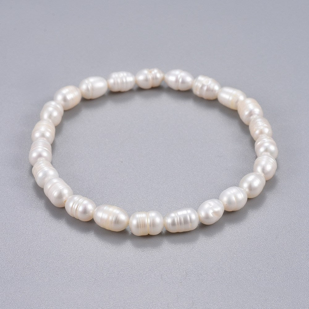 freshwater white potato pearl stretchy bracelet over grey background. 