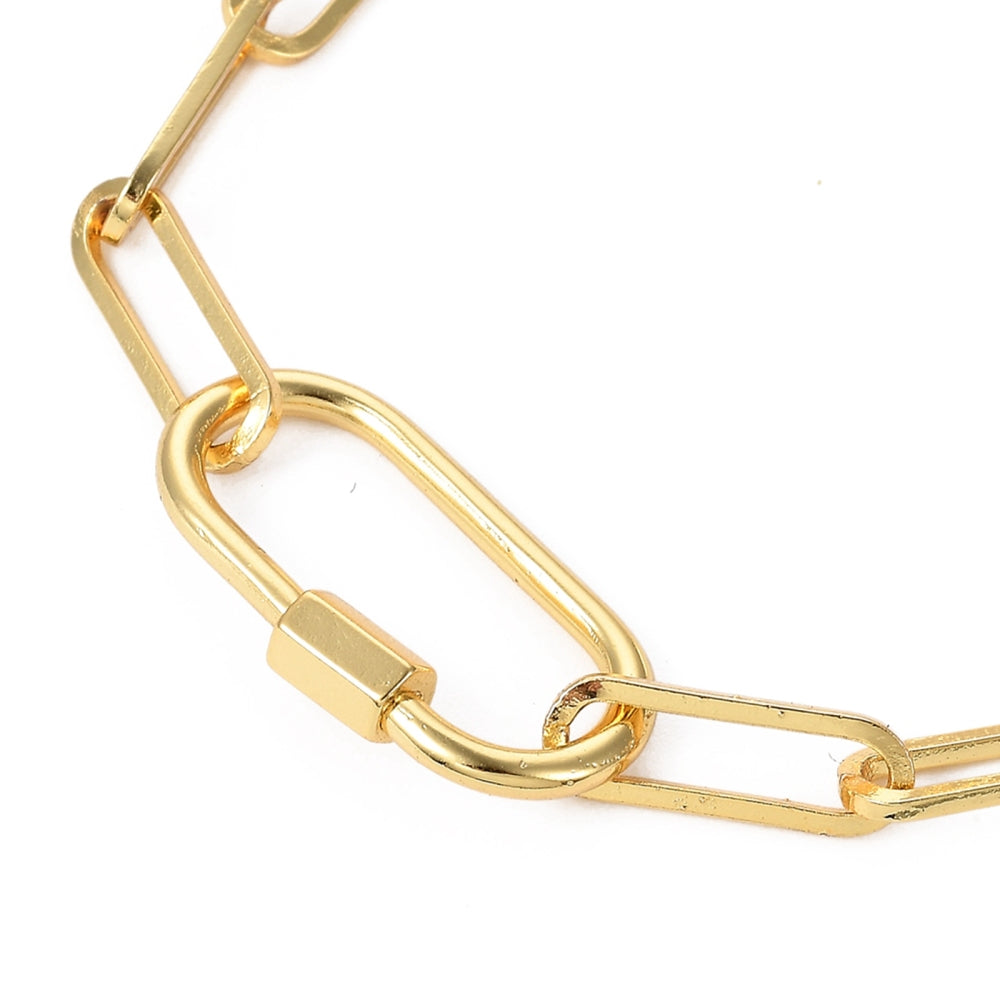 zoomed in section of golden paperclip chain bracelet with carabiner clasp over white background. 