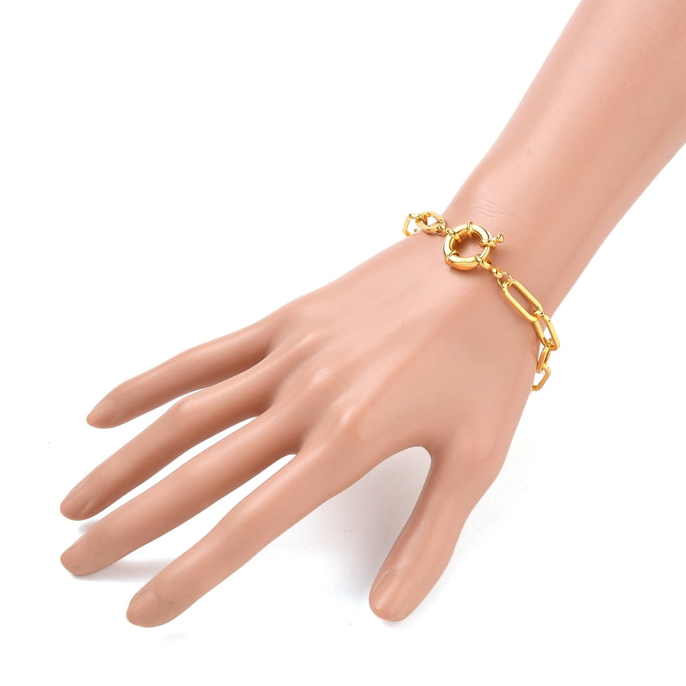 golden paperclip link bracelet with large spring ring clasp displayed on a hand against a white background. 