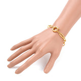 golden paperclip link bracelet with large spring ring clasp displayed on a hand against a white background. 