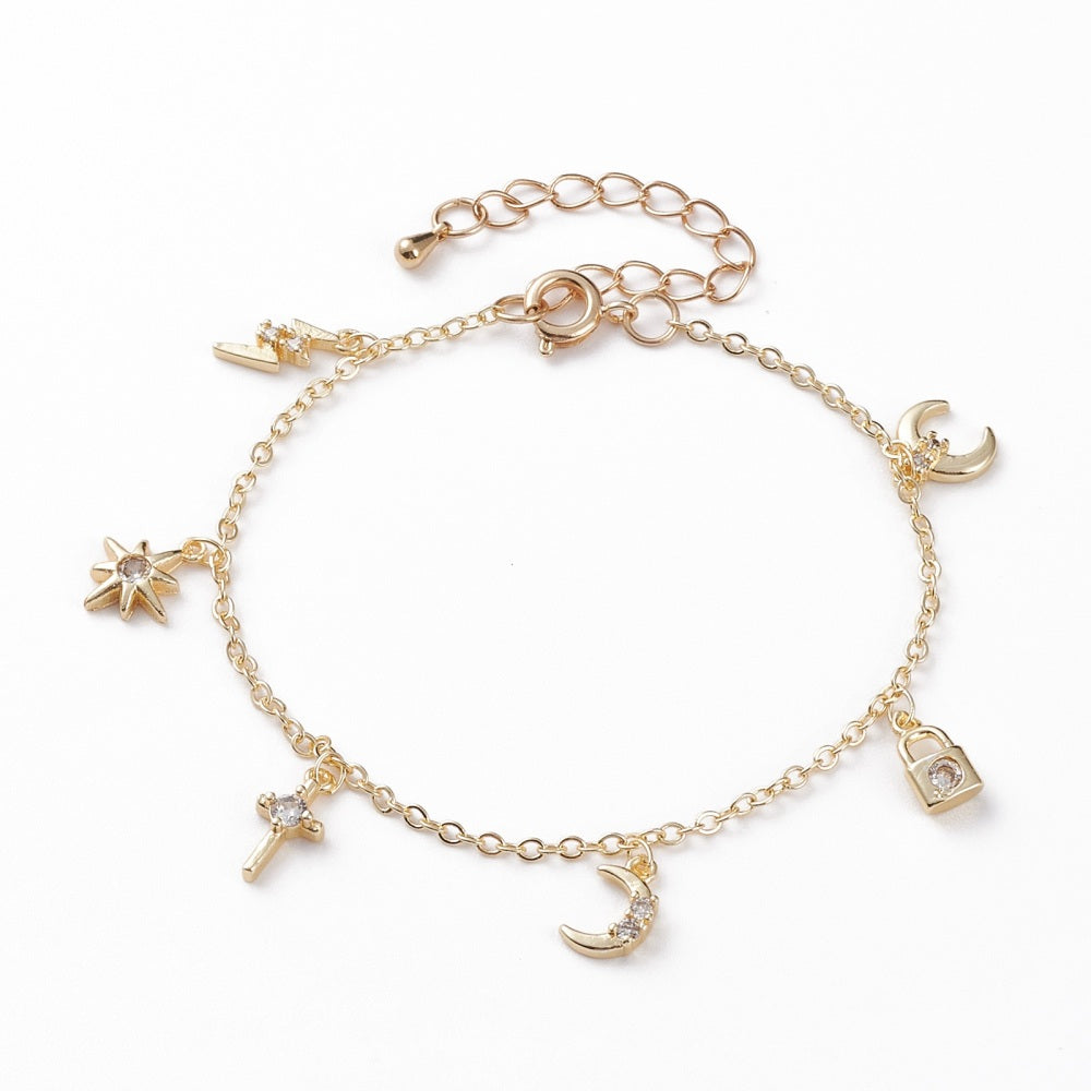 golden and clear stone charm bracelet with spring ring clasp and extender chain including a lightening bolt, star, cross, moon, padlock and crescent charms over white background. 