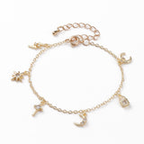 golden and clear stone charm bracelet with spring ring clasp and extender chain including a lightening bolt, star, cross, moon, padlock and crescent charms over white background. 