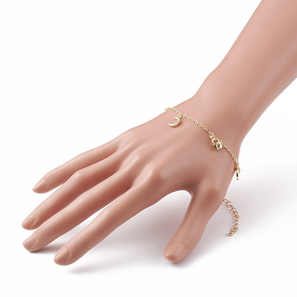gold tiny charm bracelet with displaying moon and padlock charms and extender chain on mannequin wrist over white background. 