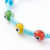 zoomed in section of light blue macrame nylon cord bracelet including red, yellow, green and light blue colored lampwork glass beads over white background. 