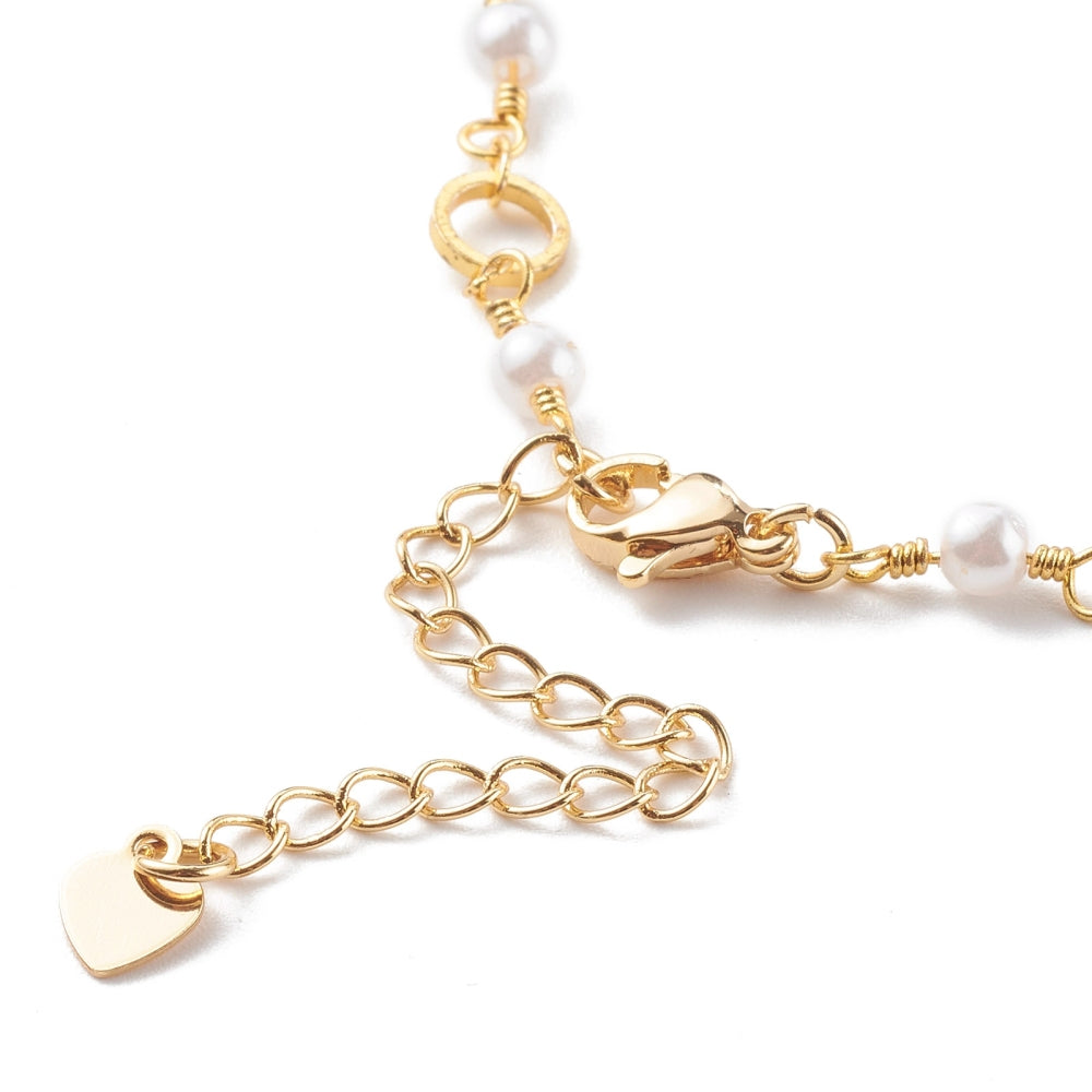 zoomed in golden lobster claw clasp and extender chain on chain bracelet that alternates ring and white faux pearl links over white background. 