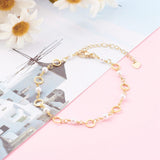golden chain bracelet alternating ring and white faux pearl links with lobster claw clasp and extender chain over light pink surface with a photo of white buildings and sky with daisies peeking in from the top left corner. 