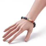 black lava rock stretch chakra bracelet featuring seven round chakra stone beads between small gold spacer beads displayed on a hand over white background. 