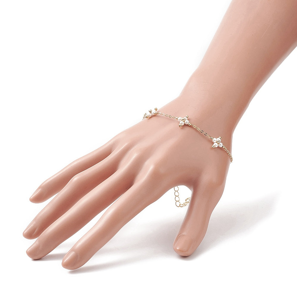 golden cable link bracelet with three white pearl beaded cross connectors  displayed on mannequin hand with white background. 