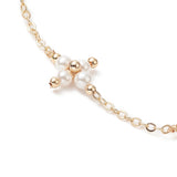 zoomed in section of golden cable link chain and white pearl beaded cross connector over white background. 