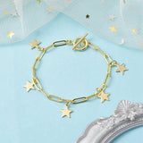golden paperclip chain bracelet with five evenly spaced star charms and toggle clasp over light blue surface  with white tulle and an antique silver frame peeking in from the edges.