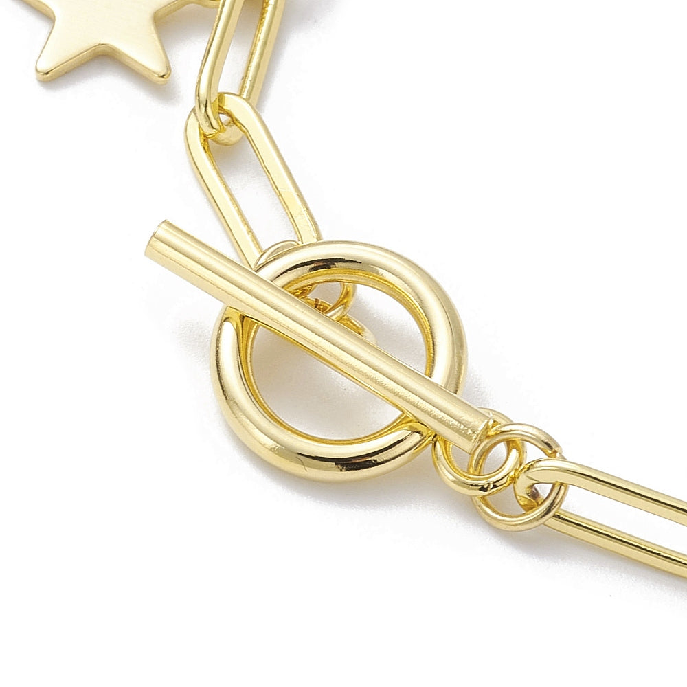zoomed in toggle clasp section of golden paperclip chain bracelet with star charms over white surface. 