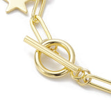 zoomed in toggle clasp section of golden paperclip chain bracelet with star charms over white surface. 