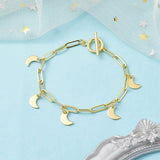 golden paperclip chain bracelet with toggle clasp and five evenly spaced crescent moon charms on a light blue surface with white tulle with gold and silver star confetti and a silver ornate frame peeking into the picture. 