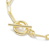zoomed in section of golden toggle clasp on paperclip chain over white background. 