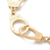 zoomed in section of golden handcuff link bracelet with the word "freedom" engraved on each cuff over white surface. 