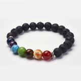 black lava rock stretch chakra bracelet featuring seven round chakra stone beads between silver double line spacer beads over a white background. 