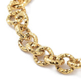 zoomed in section of golden textured rolo link bracelet on white surface. 
