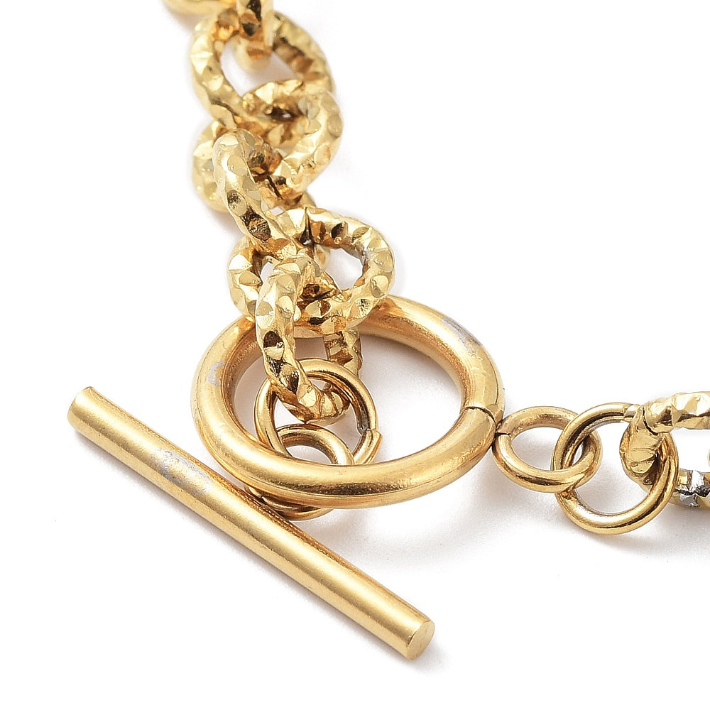 zoomed in section of golden textured rolo link bracelet with large, smooth toggle clasp on white surface. 