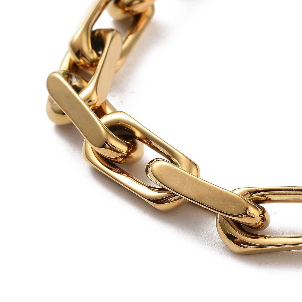zoomed in section of golden chunky, flat edge paperclip chain bracelet over white background. 