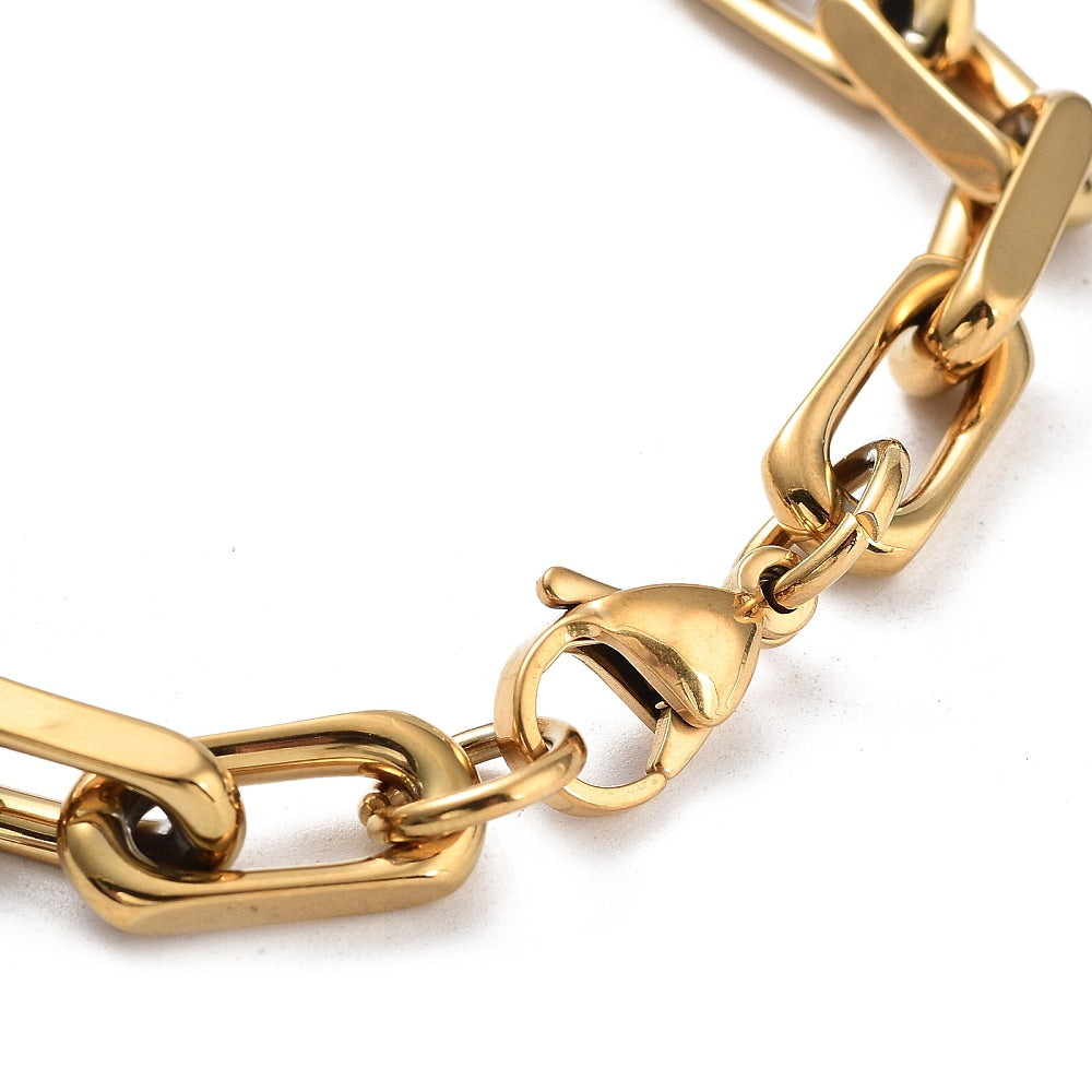 zoomed in section of golden chunky, flat edge paperclip chain bracelet with lobster claw clasp over white background. 