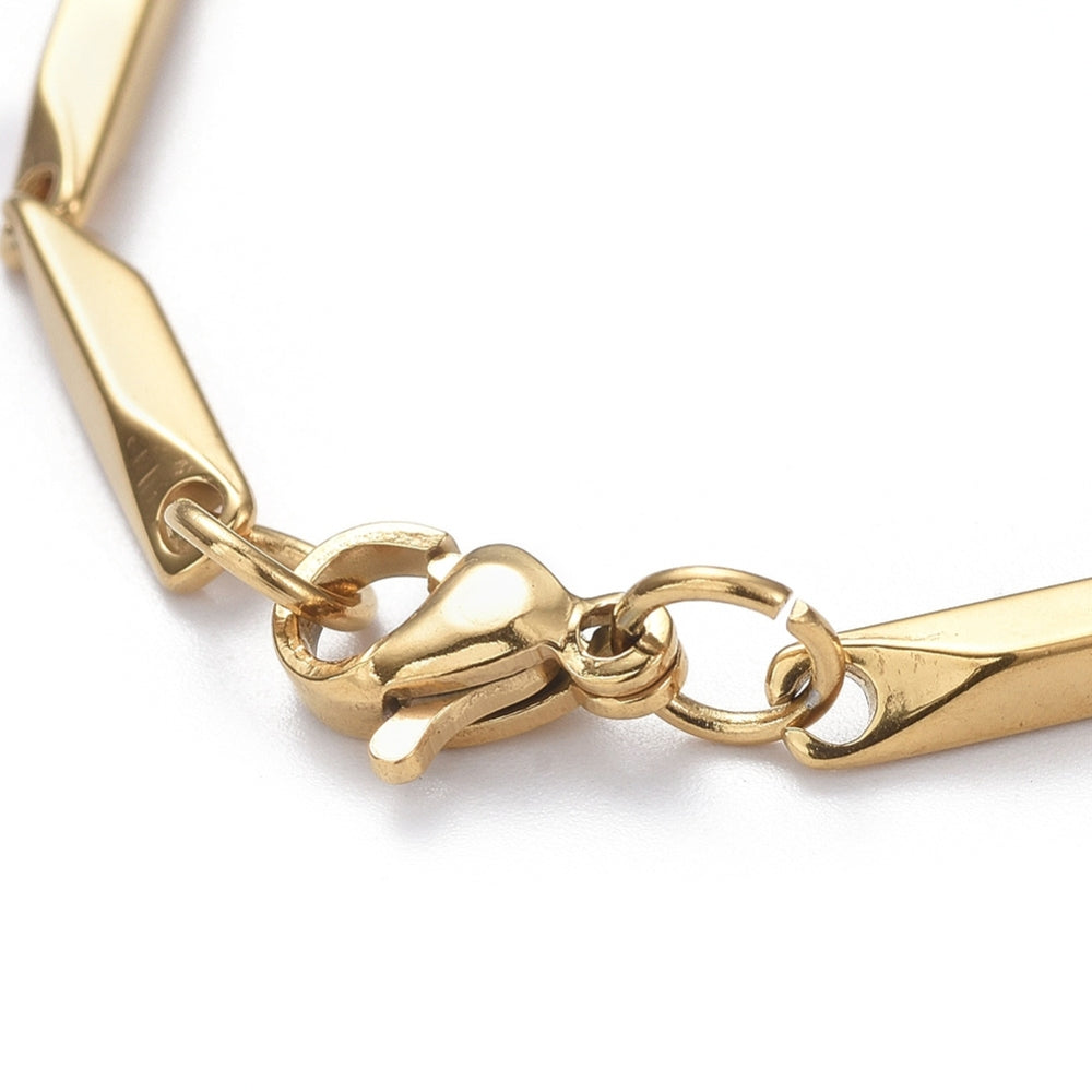 zoomed in section of golden bar link chain bracelet with lobster claw clasp over white background. 