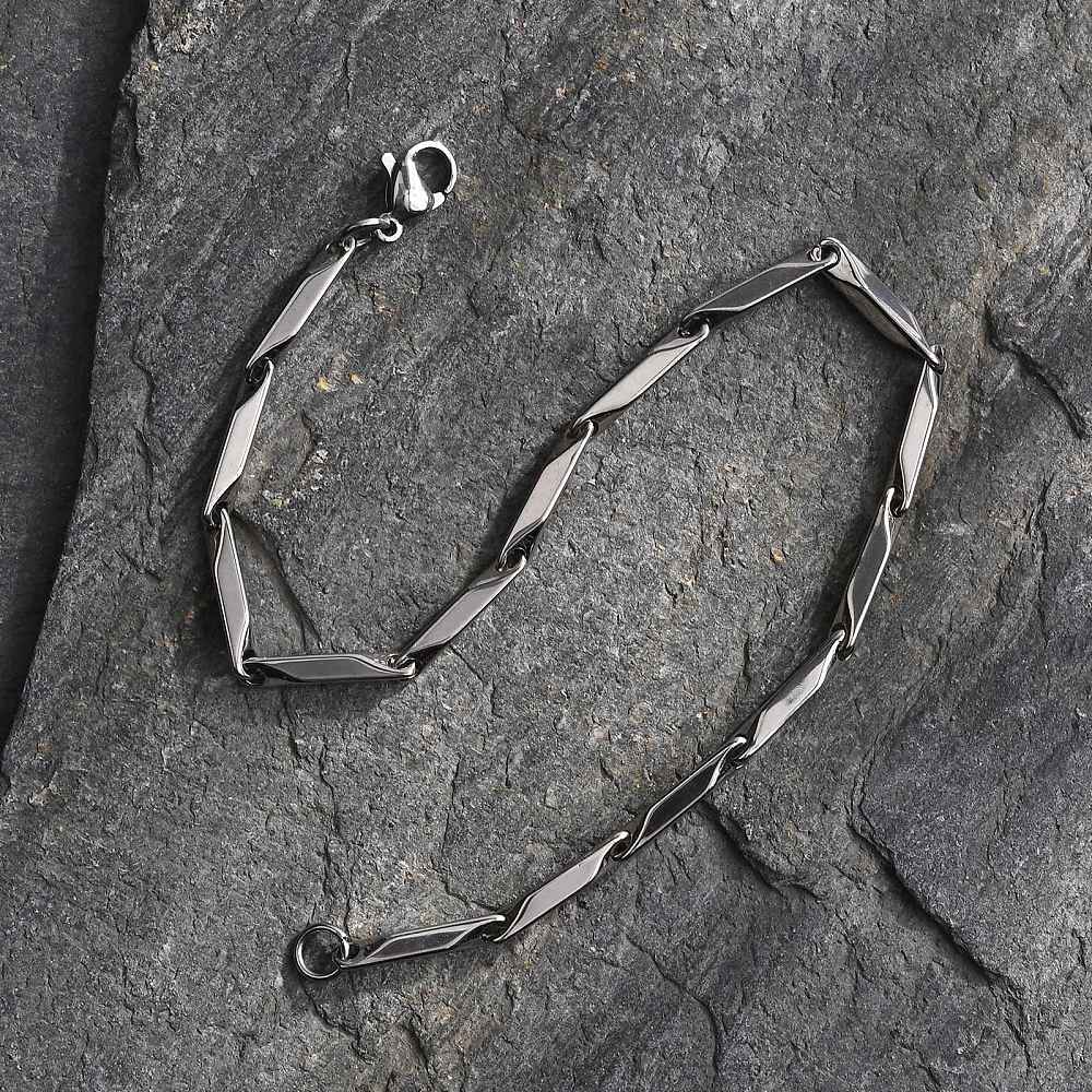 silver tone bar link chain bracelet with lobster claw clasp in "s" design on a grey rock slab. 