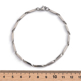 silver tone bar link chain bracelet with lobster claw clasp displayed over wooden ruler with white background. 