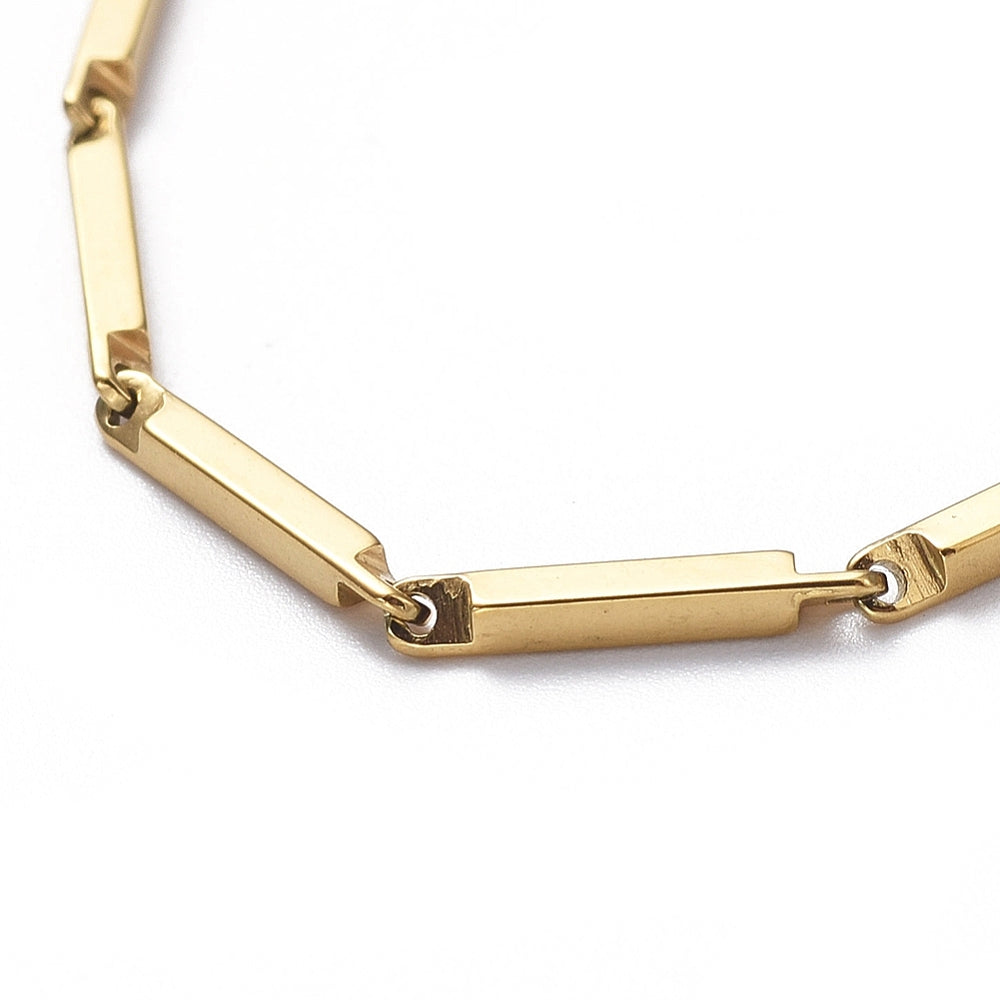 zoomed in section of golden bar link chain over white background.