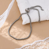silver tone bolo bracelet with stopper bead and jump rings on ends draped over a white pillow onto a cream surface with peeks of lace in corners. 