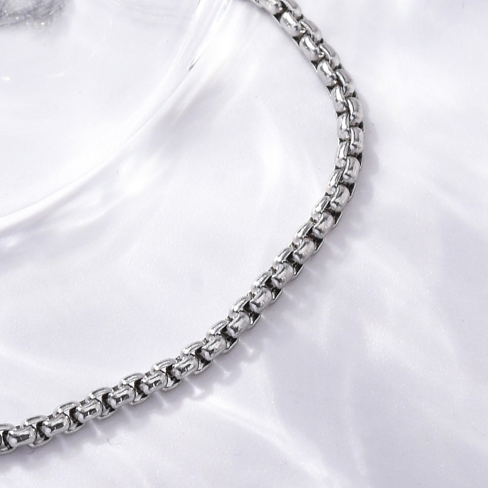 silver tone box chain over white satin surface. 