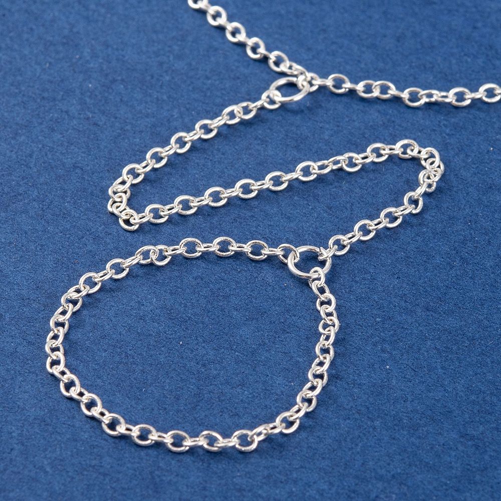 zoomed in section of silver tone hand chain bracelet on blue felt surface. 