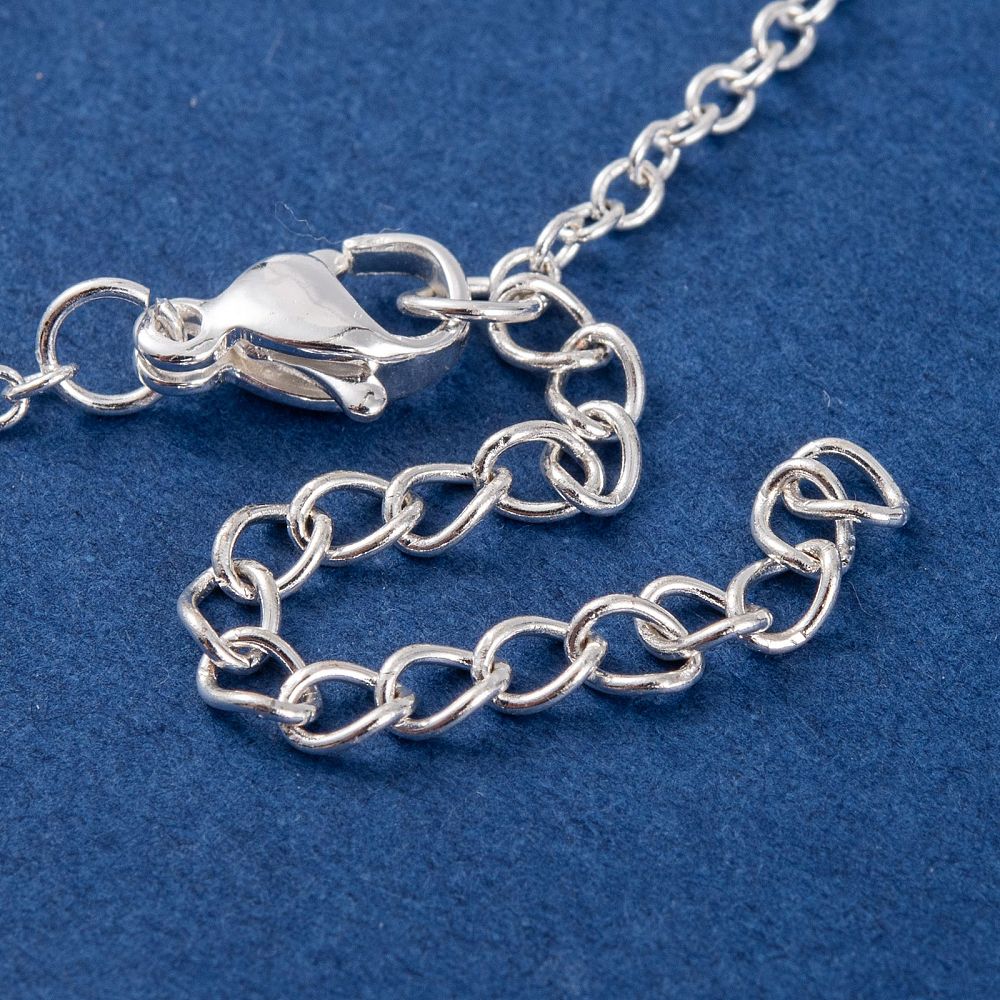 close up view of silver tone lobster claw clasp and extender chain on hand chain bracelet on blue felt surface. 