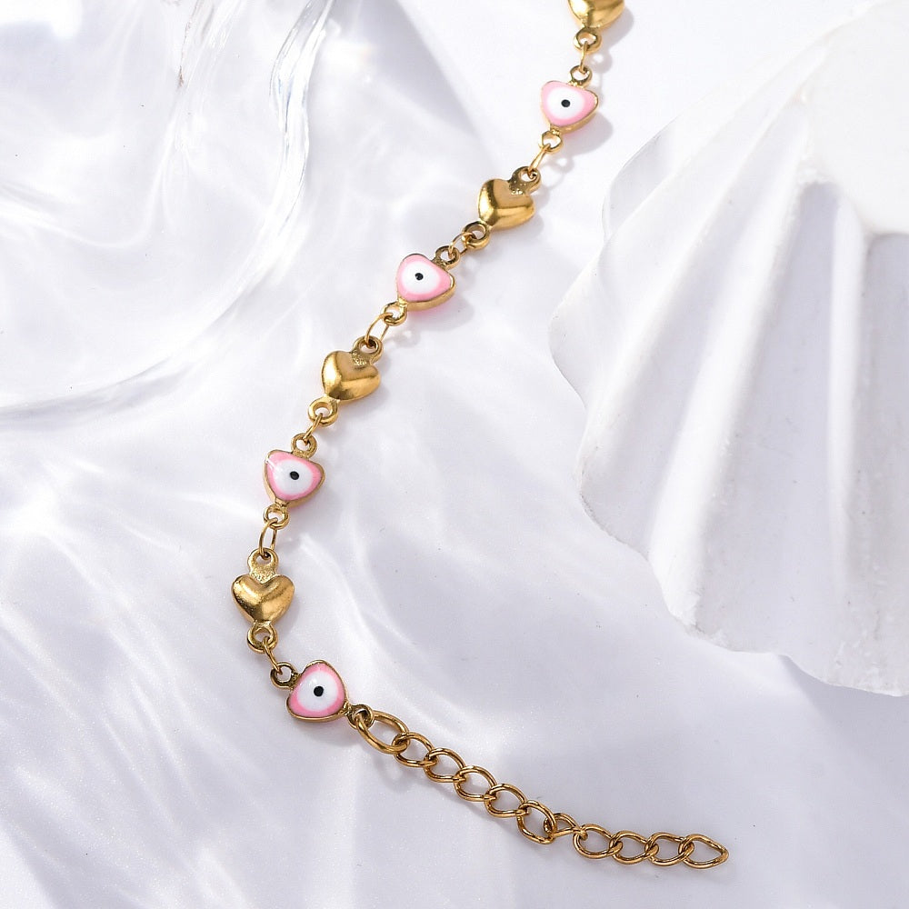 golden heart link bracelet featuring a pink evil eye on every other link plus extender chain displayed on shiny white surface.  