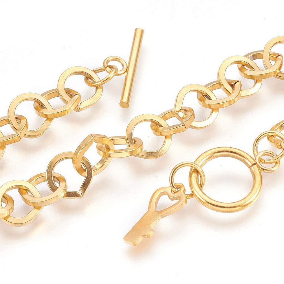 zoomed in sections of golden large cable link bracelet with toggle clasp and key charm on white background. 