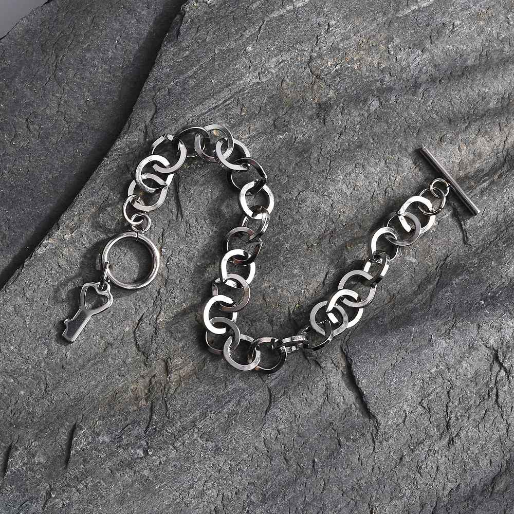 silver tone  large cable link bracelet with toggle clasp and key charm on slate rock background. 