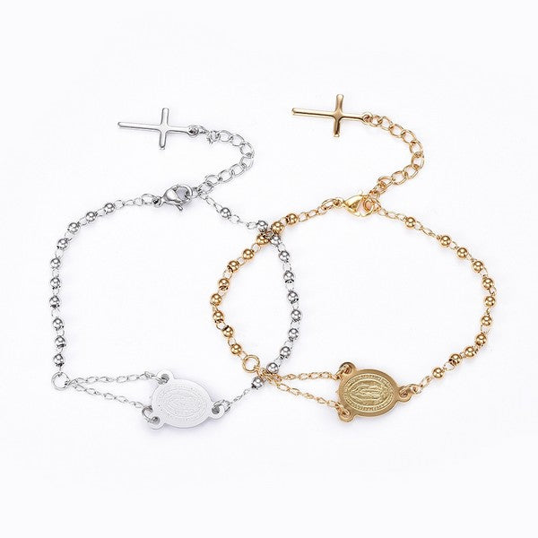 one golden and one silver tone rosary bracelet with Virgin Mary connector piece ball link chain with lobster claw claps and extender chain where a cross charm dangles from over white background,. 