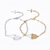 one golden and one silver tone rosary bracelet with Virgin Mary connector piece ball link chain with lobster claw claps and extender chain where a cross charm dangles from over white background,. 