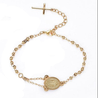 golden rosary bracelet with Virgin Mary connector piece a ball link chain with lobster claw claps and extender chain with a dangling cross charm over white background. 