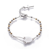 silver tone rosary bracelet with Virgin Mary connector piece a ball link chain with lobster claw claps and extender chain with a dangling cross charm over white background. 