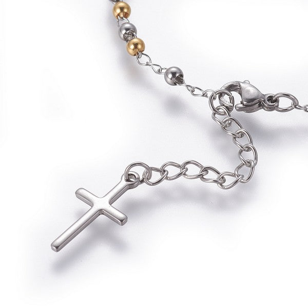 zoomed in section of rosary bracelet with extender chain and cross charm over white background. 