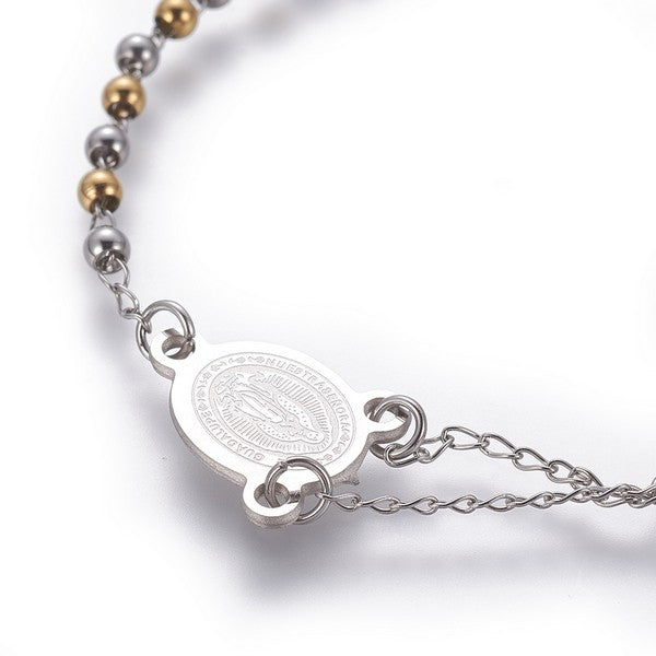 zoomed in front section of silver tone rosary bracelet with Virgin Mary connector piece a ball link chain  over white background. 